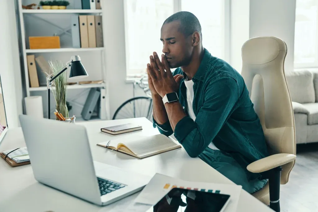 Homme au bureau qui respire profondément pour pratiquer la gestion du stress