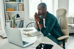 Homme au bureau qui respire profondément pour pratiquer la gestion du stress