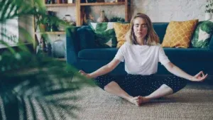 Personne assise en tailleur qui pratique la pleine conscience au salon