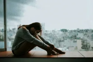 Person sitting alone by a rainy window