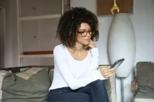 Jeune femme seule sur un canapé qui regarde son téléphone