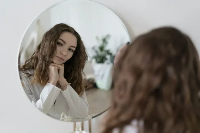 Adolescente pensive qui regarde son reflet dans un miroir